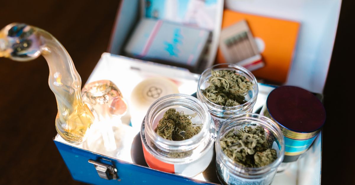 Open cannabis box containing weed, glass pipe, and rolling papers for legal use.